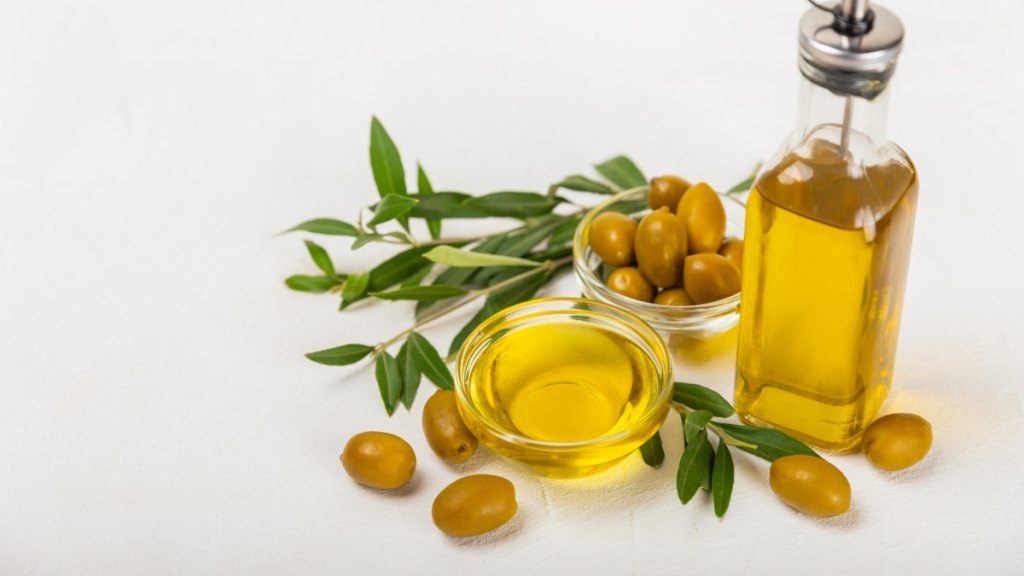 A bottle of olive oil beside a jar of olive oil and fresh olives for gardening pain