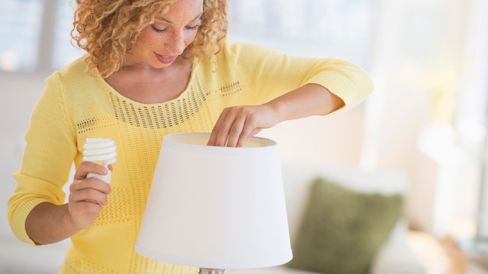 Woman changing lightbulb from lap