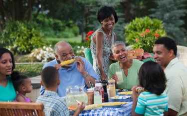 Multi-generation Black family eating at barbecue in back yard