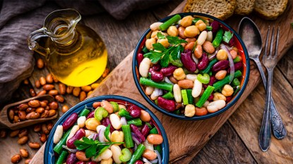 Two bowls of bean salad next to a bottle of olive oil as part of an Italian Mediterranean diet