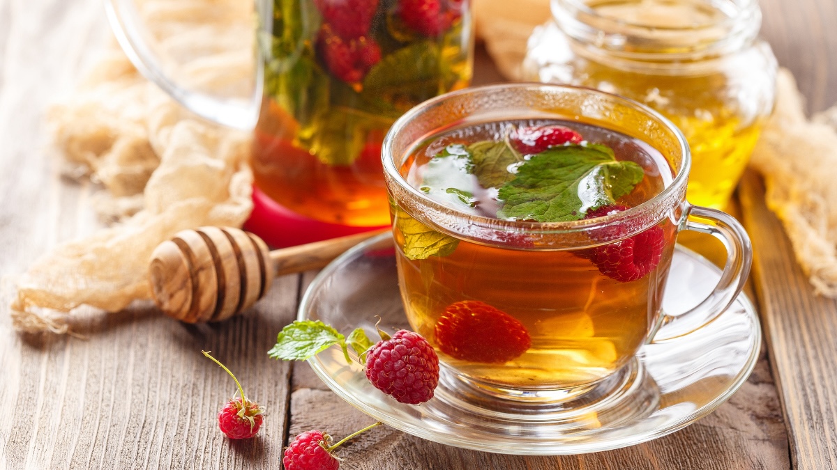 image of raspberry tea amid a few raspberries and honey