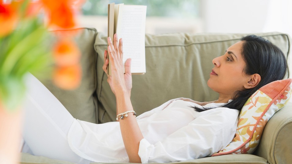 woman reading a book alone on a sofa
