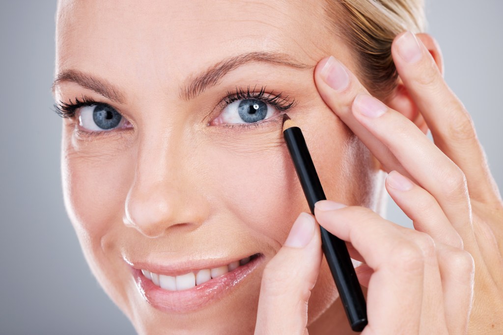Woman holding an eyeliner and is about to created a cat eye wing, which is a trick to use eyeliner for hooded eyes