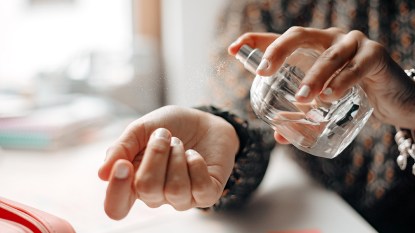 A hand spraying perfume on a wrist to make perfume last longer
