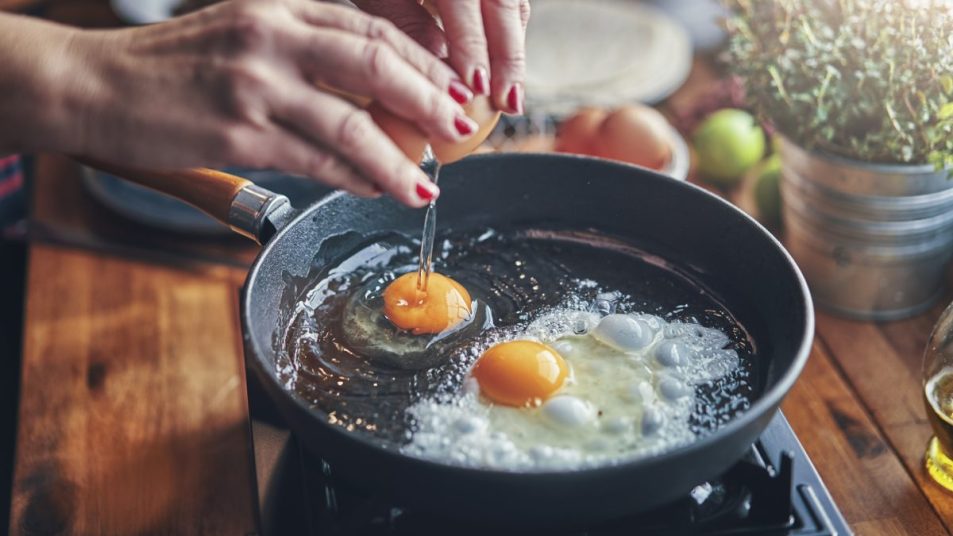 Woman frying eggs in bacon grease