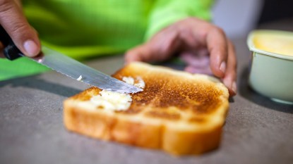 Woman's hands buttering white toast