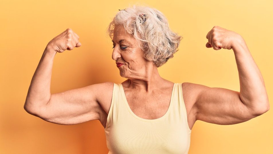 senior woman smiling and posing in strong bicep curl pose