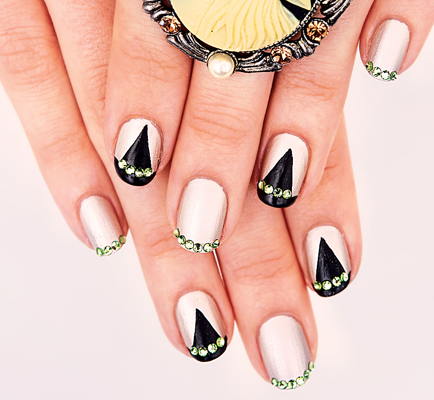 Halloween nails painted with witch hat designs and green rhinestones