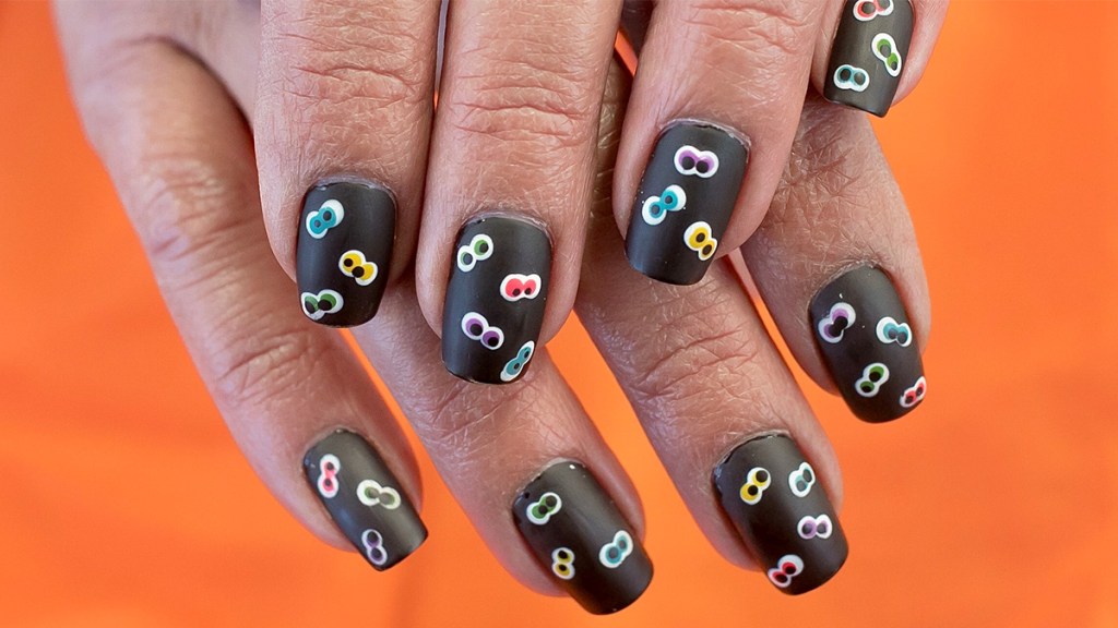 Halloween nails painted black with multi-colored googly eyes