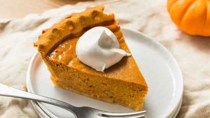 A slice of sour cream pumpkin pie topped with whipped cream