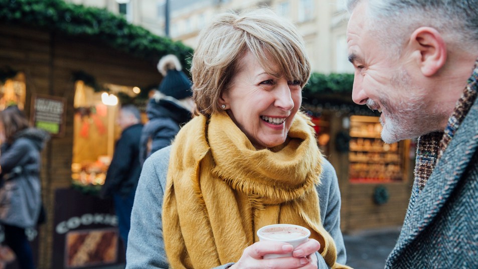 Mature couple are enjoying a cup of coffee as they explore the town christmas market.