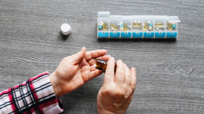 woman taking vitamins out of pill keeper