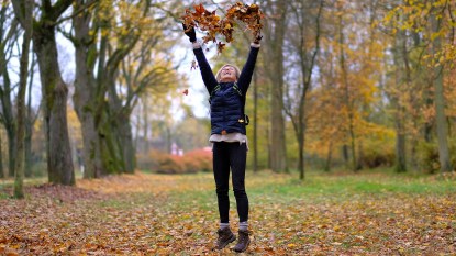 woman jumping in fall leaves