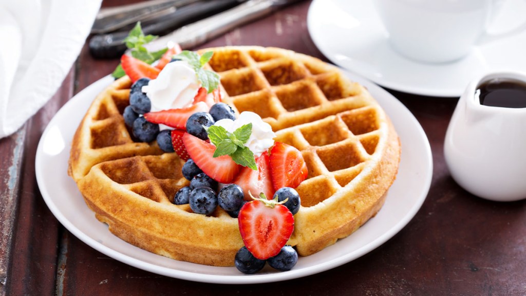 Waffle on a plate topped with berries and yogurt as part of 80/20 diet plan