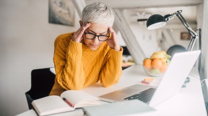 woman wearing reading glasses with headache