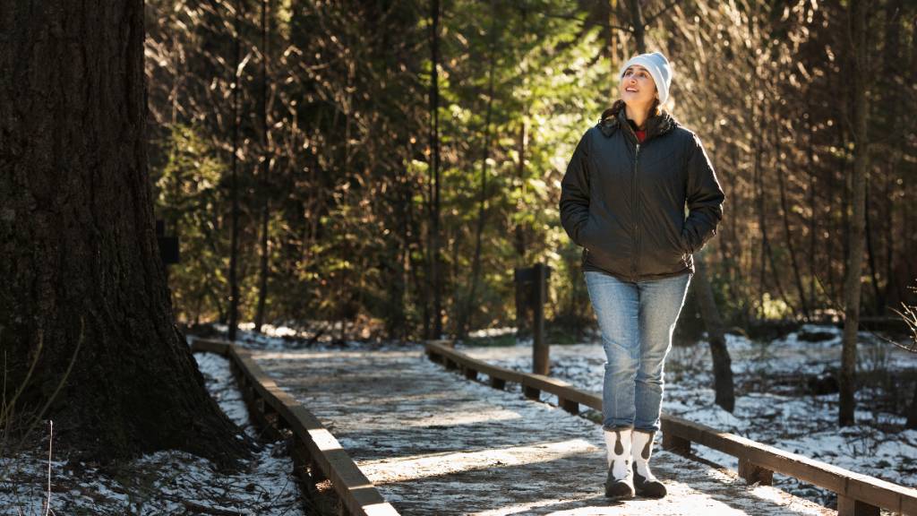 Woman happily takes a walk surrounded by trees in the morning during winter
