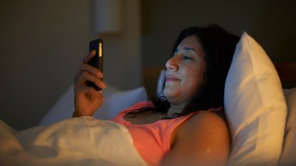 mature woman in bed looking at her phone