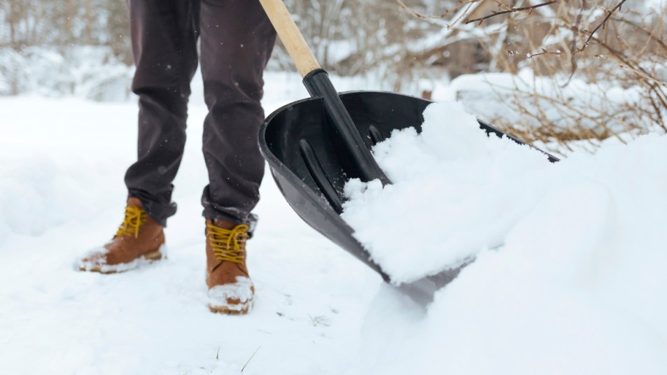 person shoveling snow, close up on black snow shovel