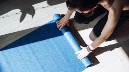 woman rolling out yoga mat, bird's eye view