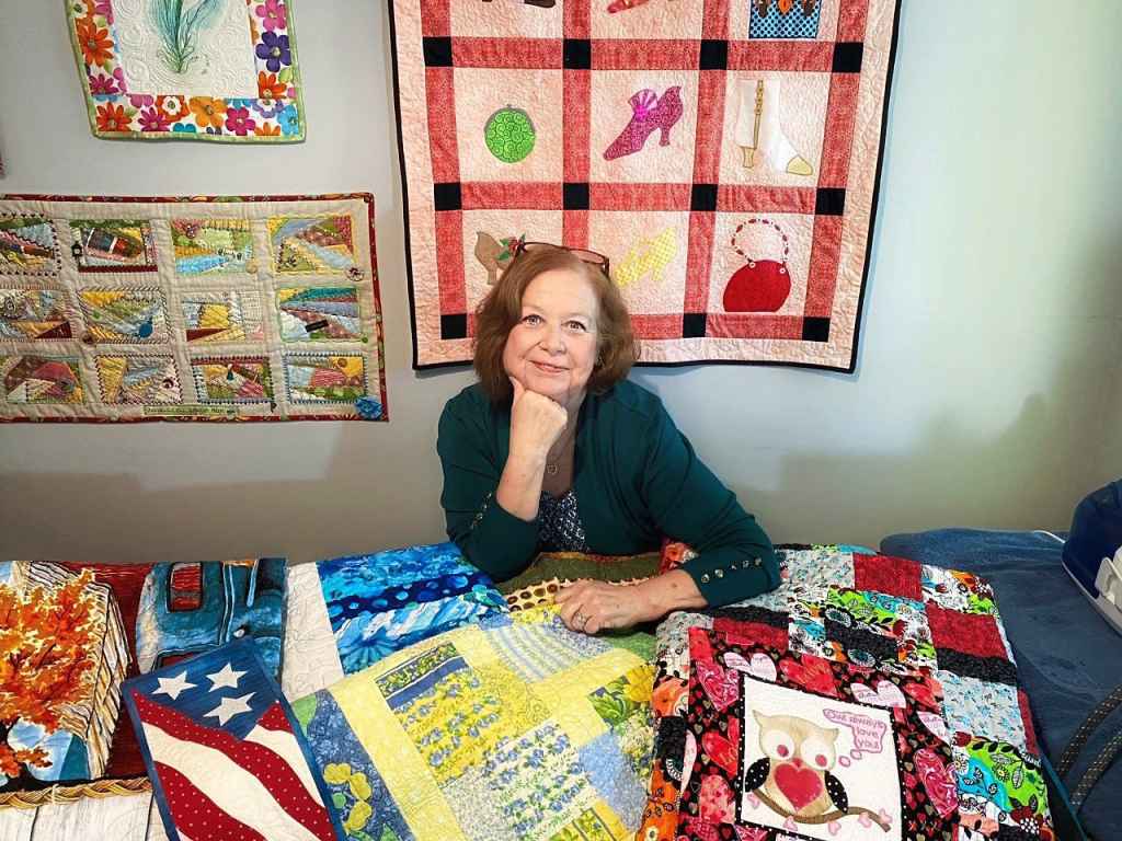 Carol Ann Ferrari-Rogers with her quilts benefits of quilting