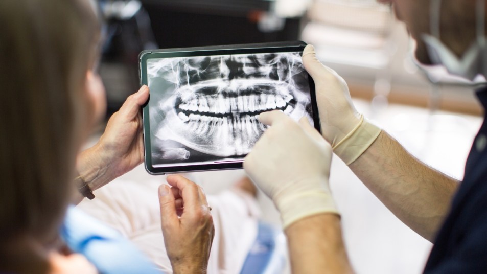 woman and male dentist looking at her teeth x-ray on a screen, inspecting oral hygiene