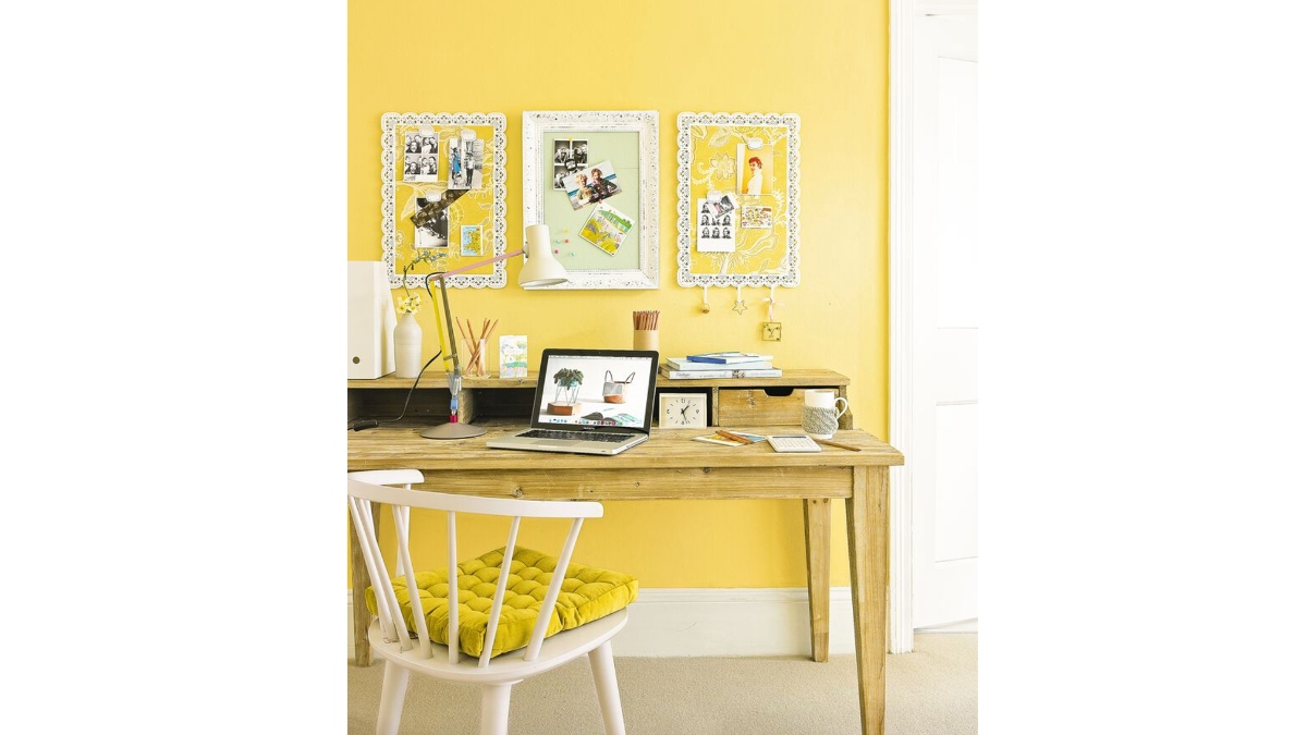 decorated yellow room with desk and hanging picture frames