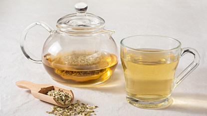 A teapot and mug of fennel tea beside fresh fennel seeds