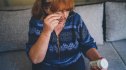 mature woman with red hair looking at label on prescription medicine