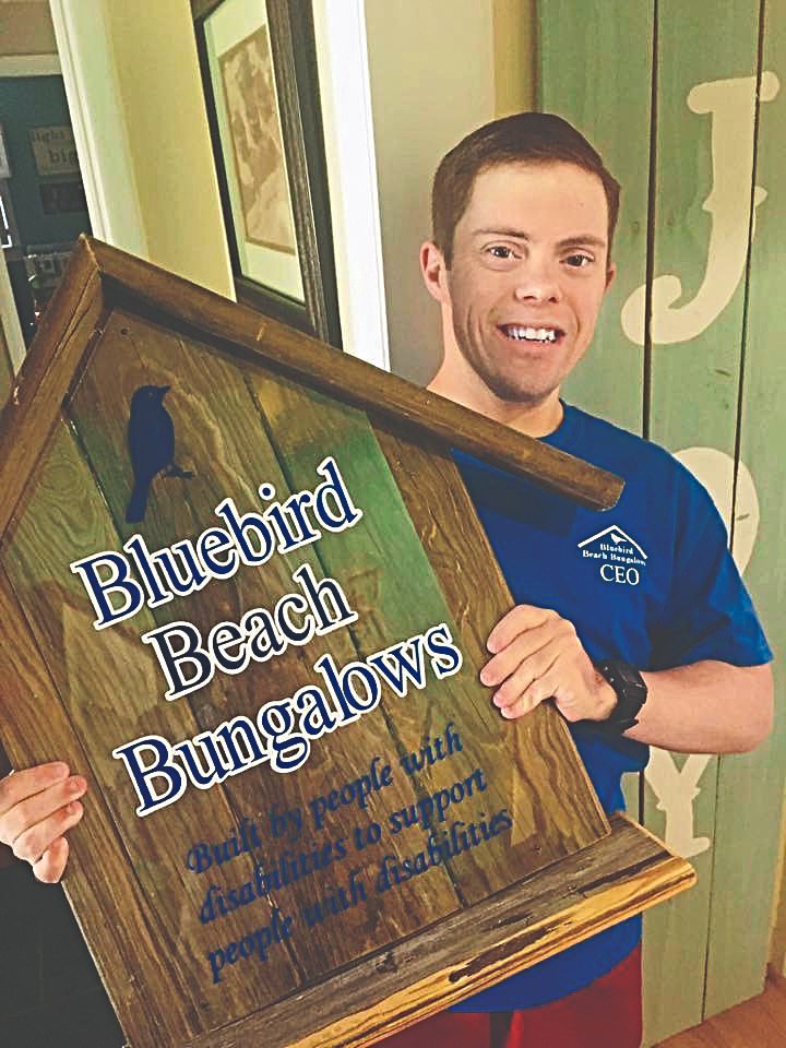 Stephen holding up Bluebird Beach Bungalows sign