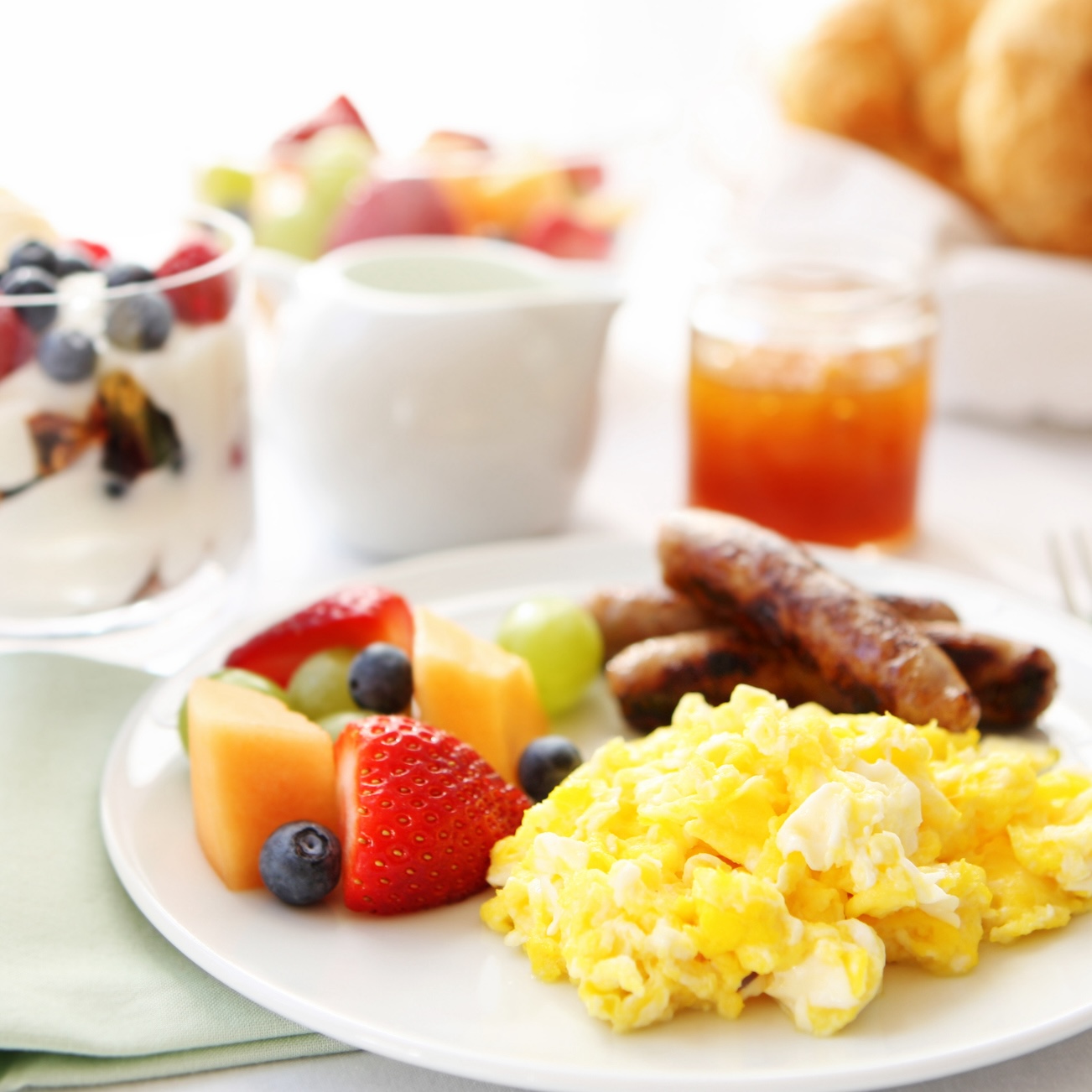 Healthy high-protein breakfast with eggs, sausage and Greek yogurt with fruit on plate