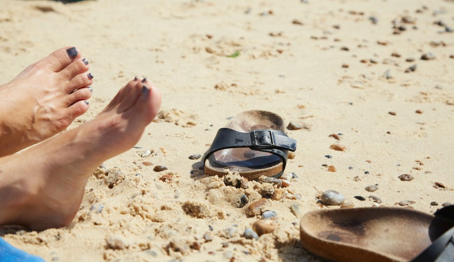 Woman relaxing on the beach with her sandals kicked off