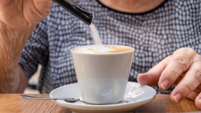 senior woman pouring sugar into her coffee