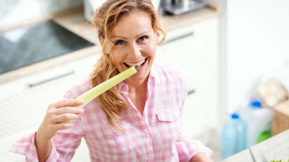 Woman biting into a stalk of celery