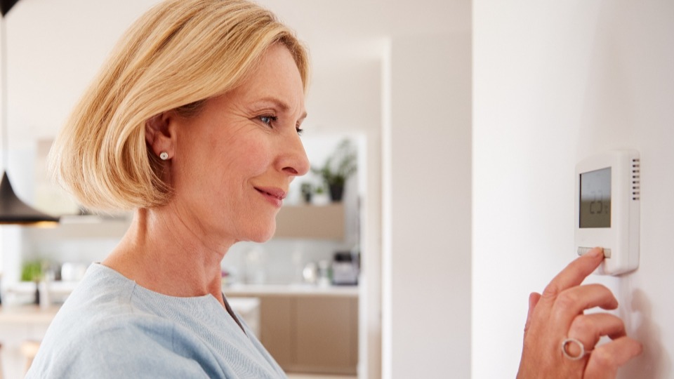 A woman lowering the temperature of her AC to save money