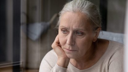 mature woman staring out a window, concerned expression, suffering from depression or Alzheimer's