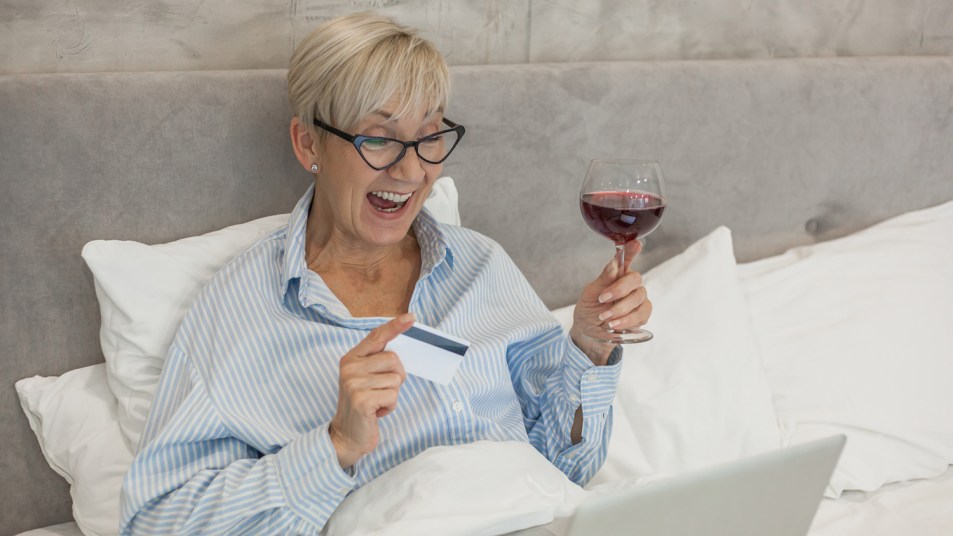 woman drinking wine and online shopping in bed