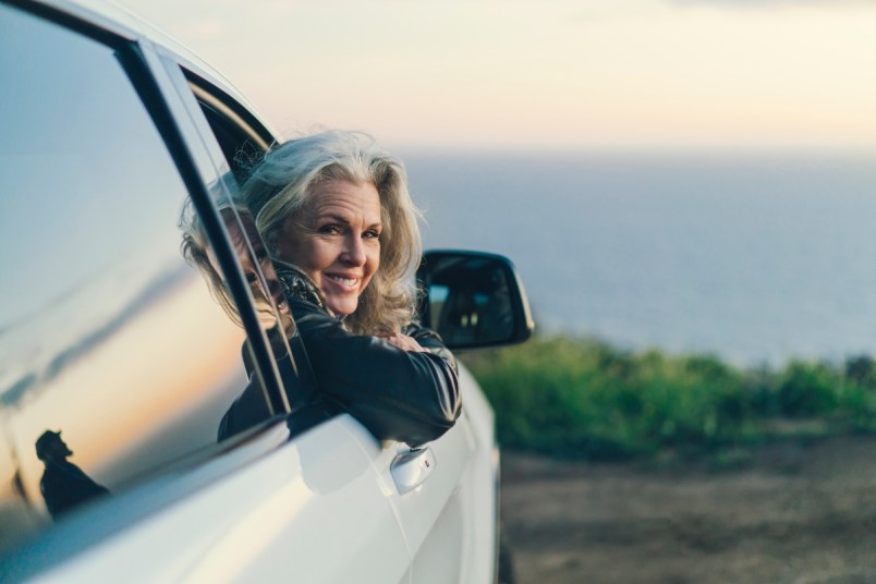 Mature woman smiling and leaning out of car window