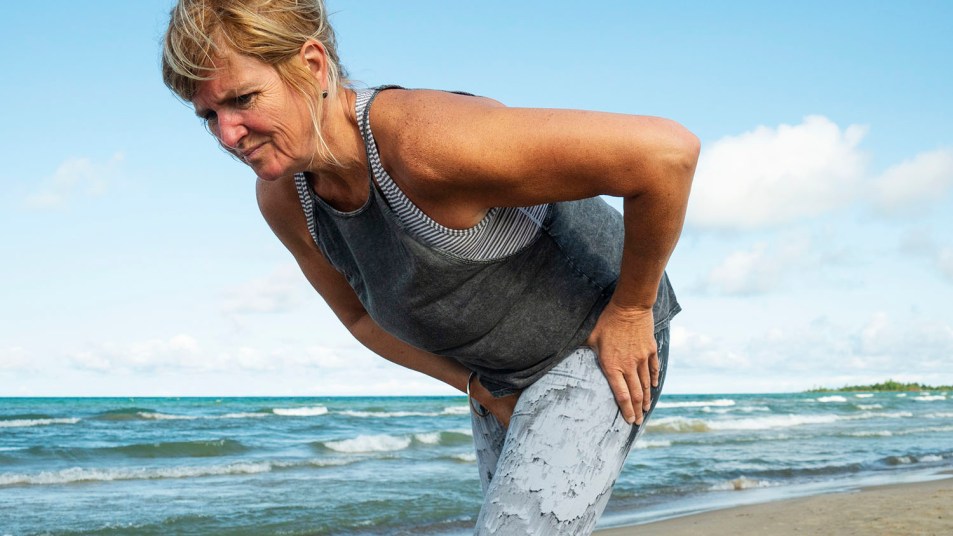A mature woman in her fifties experience hip pain during a morning run
