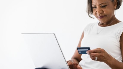 Mature business woman carefully checks numbers on credit card