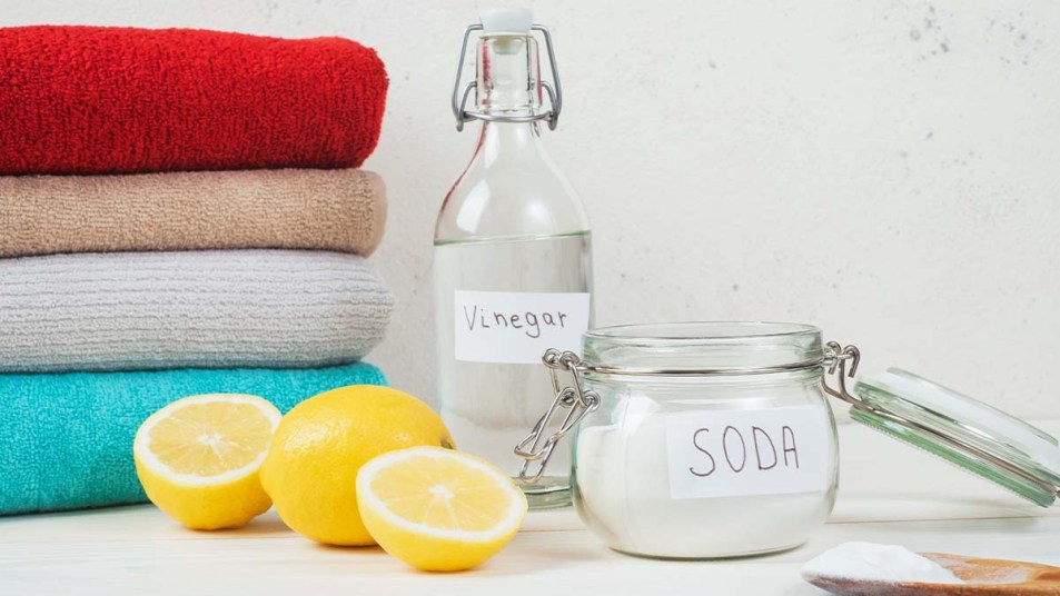 Baking-soda-in-jar-vinegar-cut-lemon-folded-towel-on-a-white-background