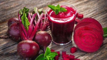 Beetroot next to a glass of beet juice on a wooden table, which has health benefits for females