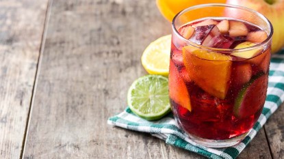 Single Serve Red Sangria in a glass next to lime and lemon rounds