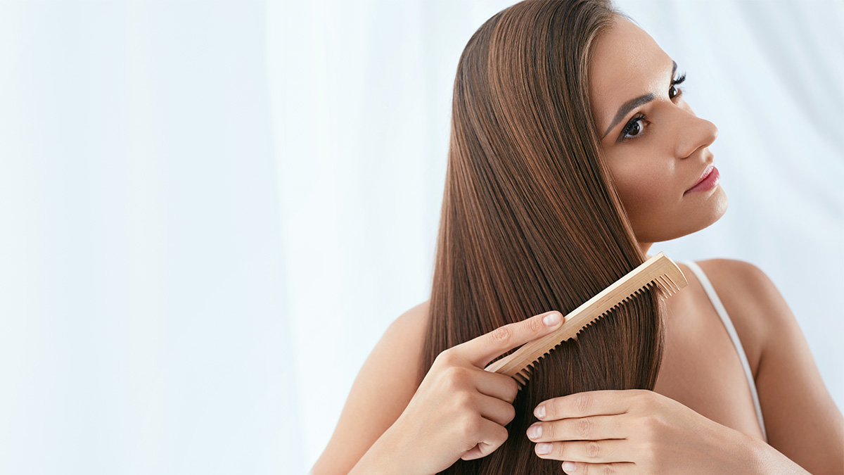 Brunette woman brushing her hair after using a DIY coconut oil treatment