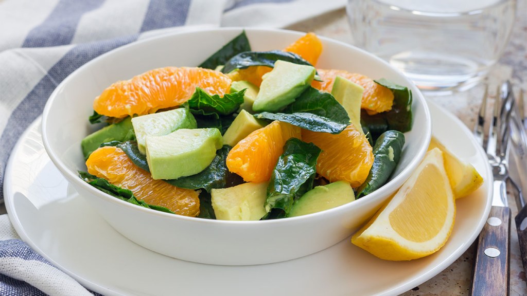 Schüssel mit Salatblättern, garniert mit Avocadostücken und Orangenstücken, perfekt für Menschen, die ihre Aufnahme von Lebensmitteln mit zähflüssigen Ballaststoffen erhöhen möchten