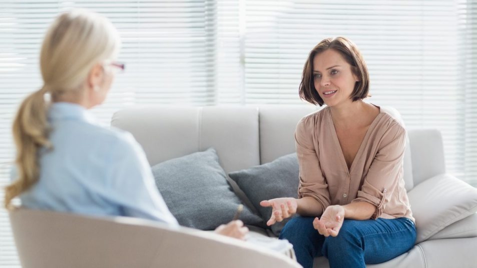mature female life coach talking to mature client on couch