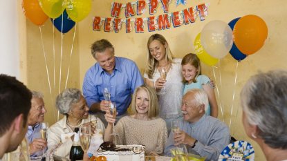 mature woman at her retirement party surrounded by friends, toasting with champagne