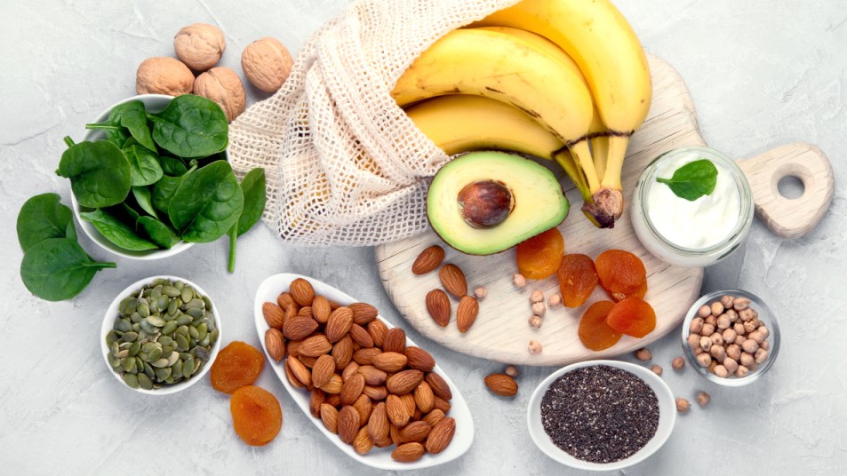 A table full of potassium-rich foods such as bananas, leafy greens, nuts, avocado, yogurt and more