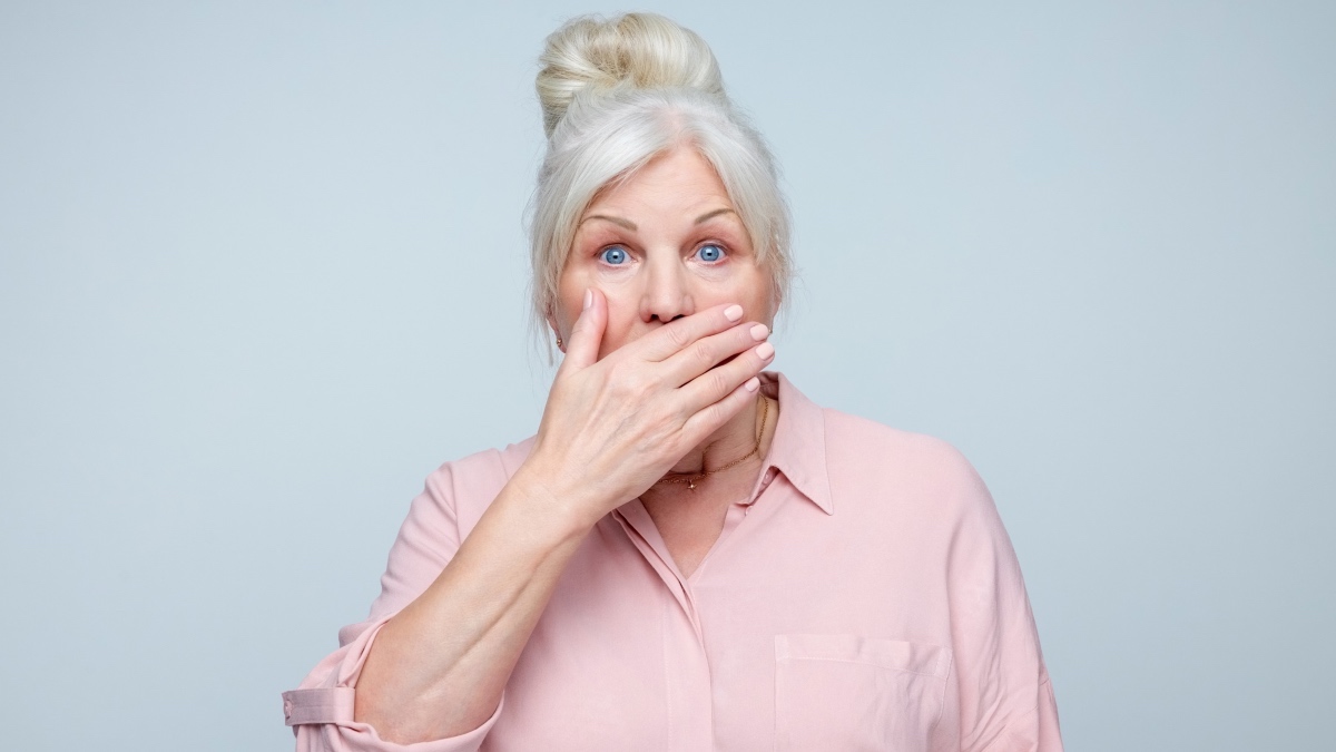 A mature woman covering her mouth with her hand due to bad breath
