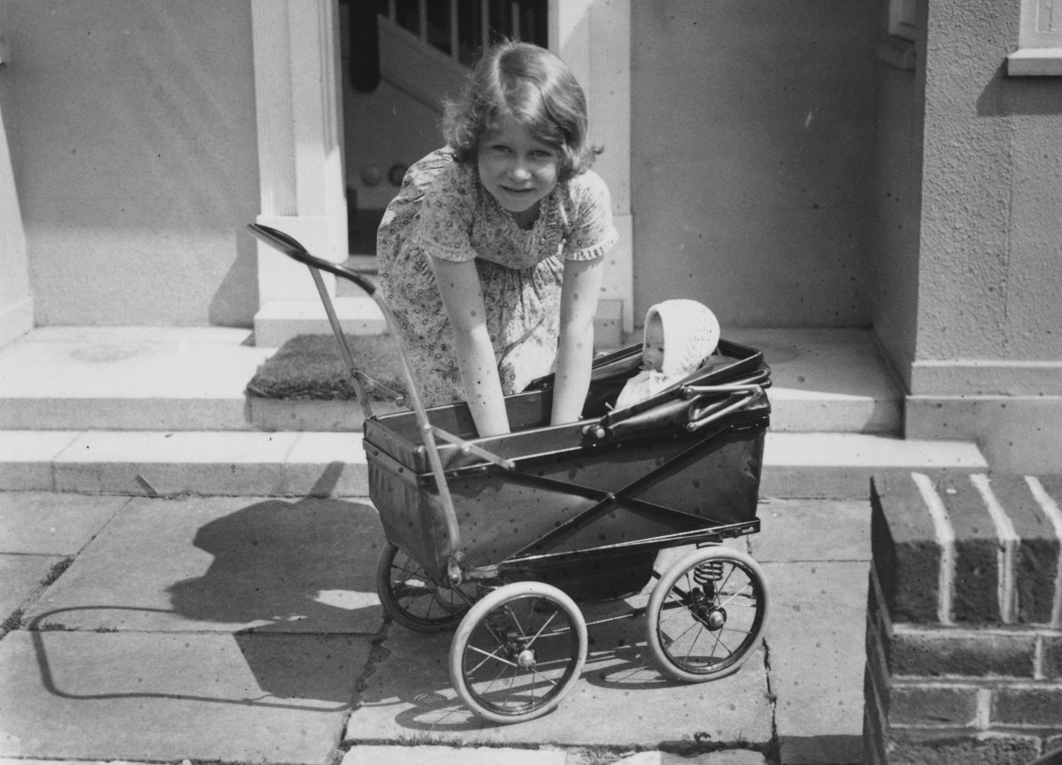circa 1933: Princess Elizabeth playing with a doll in a toy pram outside the Welsh House