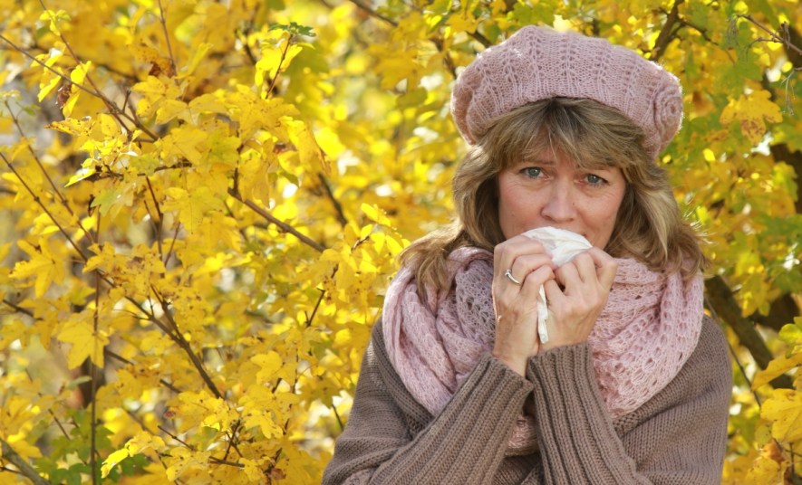 Mature woman blowing her nose in the fall